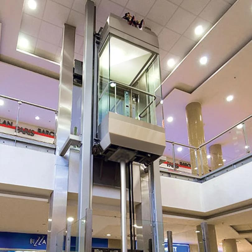 Hydraulic glass lift running through a shopping mall atrium